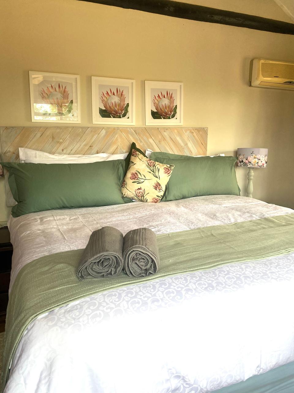 Main en-suite bedroom with wooden headboard and green cushions at Blesbok Lodge