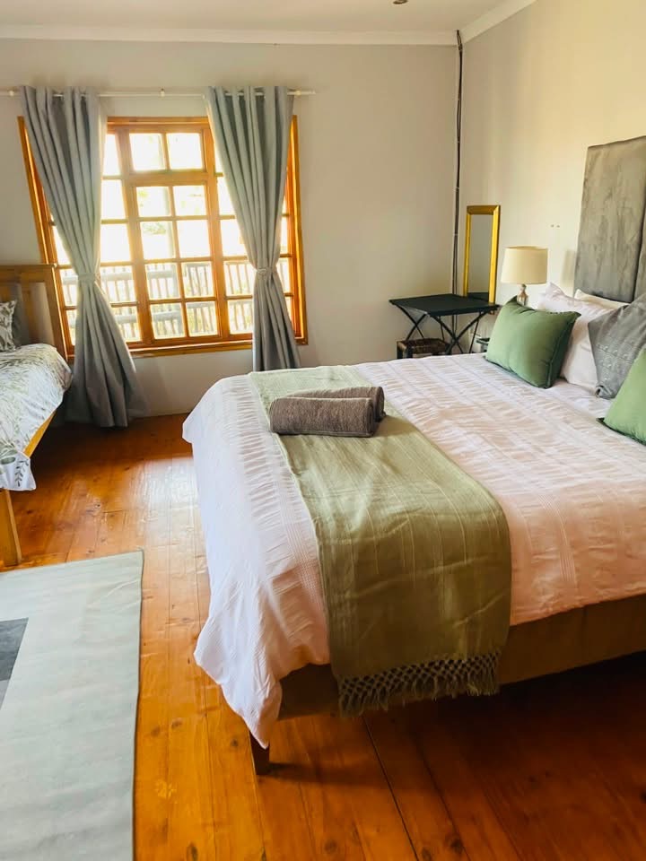 Bright main bedroom with green linen accents and wooden floors at Acacia Lodge
